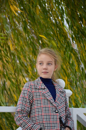 cute beautiful girl in a stylish plaid coat on a walk in the autumn park. a slight smile on his face, curly hair naughty from the wind. active lifestyle and outdoor activitiesの写真素材