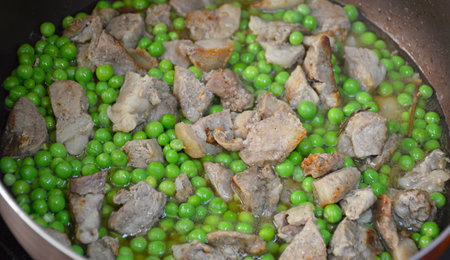 cooking pork meat and green peas with onions in a pan at home. tasty and healthy food, a combination of meat and vegetablesの写真素材
