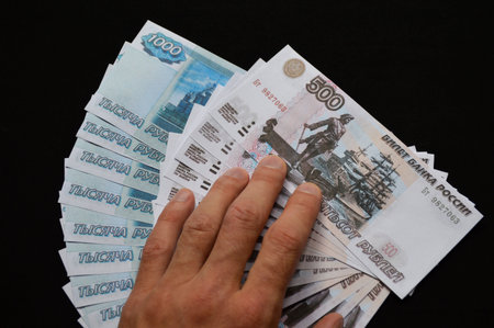 man's hand on the Russian rubles laid out in faith on a black background. purchase, sale, currency...