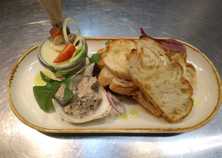 liver and poultry pate and ruddy toast on a large platter. next to slices of tomato, onion rings and sprigs of greens. toasted bread and chicken pate for breakfast, lunch or dinnerの写真素材