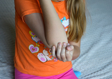 the girl is holding her elbow due to severe pain from the injury. pain in joints and muscles. injury at home or in sports. treatment, warming and massagesの写真素材
