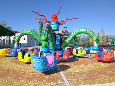 children's carousel in the shape of a multi-headed dragon. rest and entertainment for children in the city park. swings and rides for fun during the holidaysの写真素材