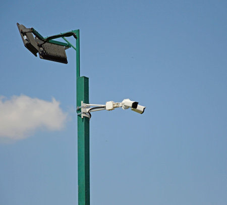 street lamp with CCTV cameras on a metal pole against blue sky. modern LED street lamp with cctv...