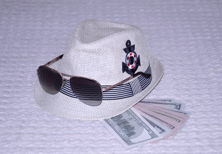straw hat, dollar bills and sunglasses. some wardrobe items and necessary things during a summer holiday in the fresh air. protection of the head and eyes from the bright, scorching sunの写真素材