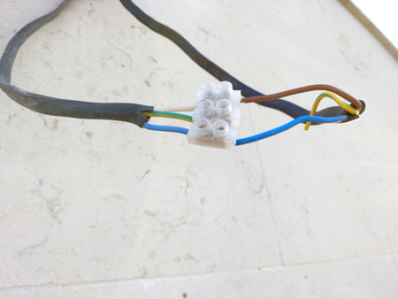 Electrical wiring connected via a plastic terminal block. Several wires are secured in the terminals, their insulation damaged or exposed in places. The wiring appears temporary or poorly done.の写真素材