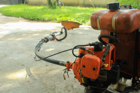 Used lawn mower sits on the concrete patio of a house ready to be used to mow the lawnの写真素材