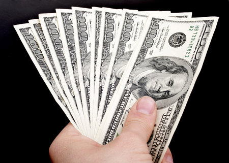 american dollars in hand on a black background