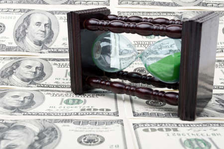 hourglass and money with dolars as a backgroundの写真素材