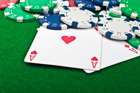 two aces and poker chips on a green felt