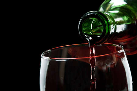 pouring red wine isolated on a black backgroundの写真素材