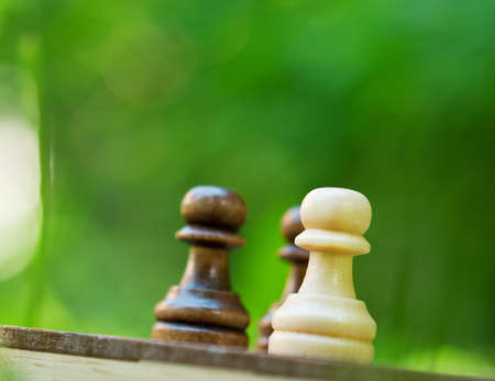 chess pawns on the board on green backgroundの写真素材