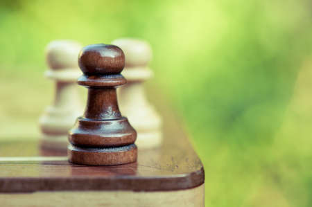 chess pawns on the board on green backgroundの写真素材