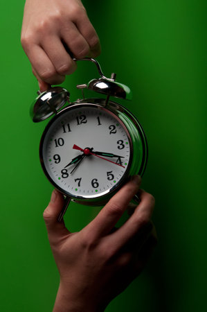 woman holding alarm clock on green background