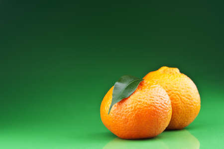 fresh orange mandarins on green backgroundの写真素材