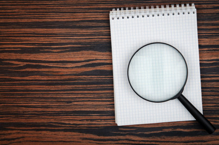 notebook and loupe on background