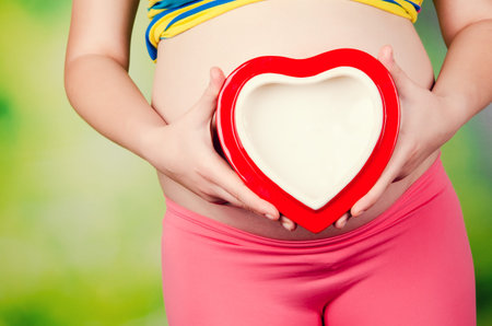 pregnant woman holding red heart
