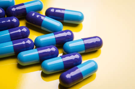 blue medical capsule on yellow backgroundの写真素材