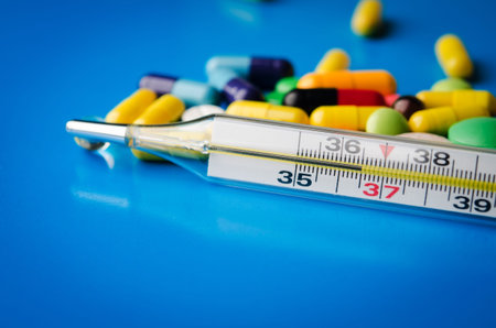 mercury thermometer and pills on blue background