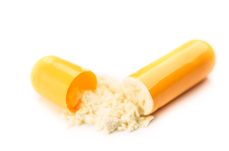 open yellow capsule isolated on white backgroundの写真素材