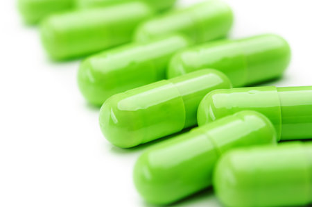 closeup of green pills capsules isolated on whiteの写真素材