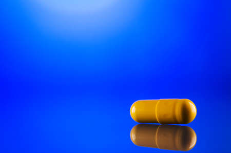 one yellow capsule on glass backgroundの写真素材