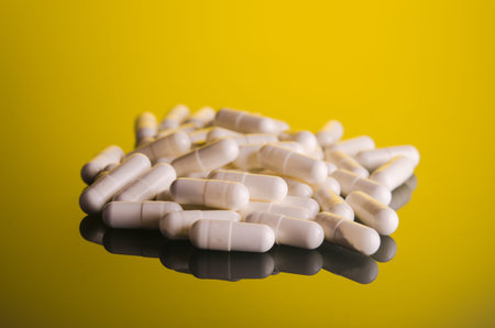 pile of white pills on yellow glass background