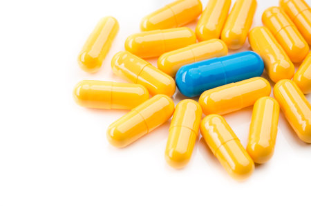 one blue and yellow capsules isolated on white background