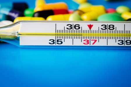 mercury thermometer and pills on blue backgroundの写真素材