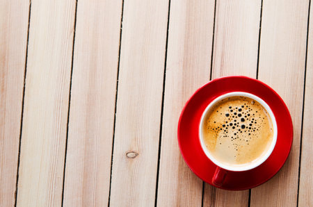 red cup of coffee on wooden table