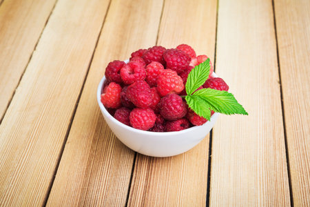 fresh raspberries in plate on wooden table