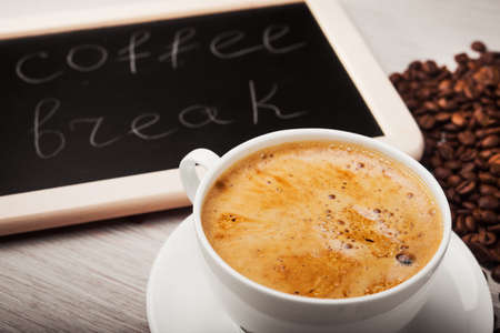 a cup of organic coffee with beans and boardの写真素材