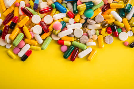 Colored pills on yellow background. Top view.の写真素材