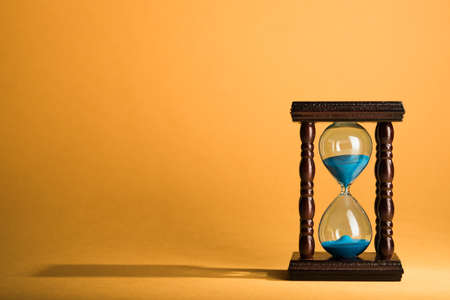 Hourglass clock on yellow vintage backgroundの写真素材