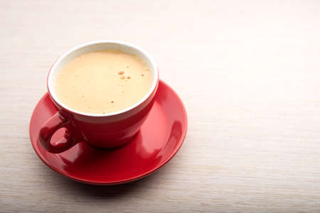 Red cup of coffee with frothy milk on tableの写真素材