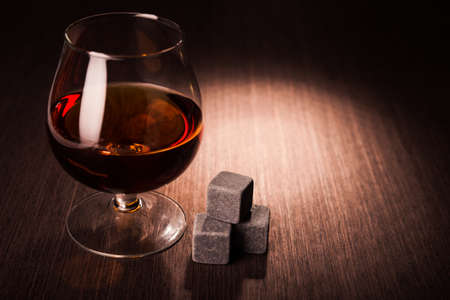 Cognac glass on wooden table. Dark alcohol background.の写真素材