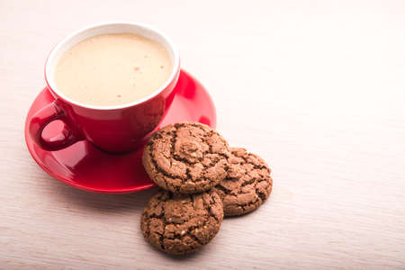 Cup with coffee and chocolate cookie on tableの写真素材