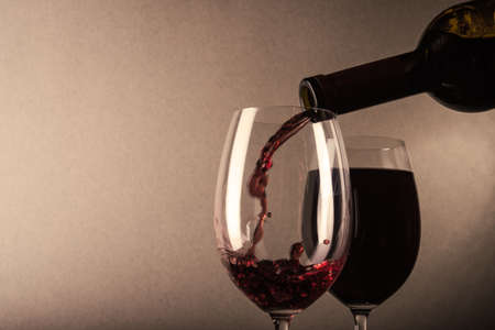 Red wine poured into a glass on backgroundの写真素材