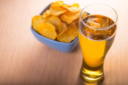 Glass of beer and chips on tableの写真素材