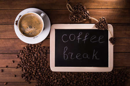 Cup of coffee, beans and board with text. Top view.の写真素材