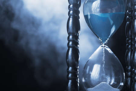 Hourglass clock and smoke on dark backgroundの写真素材