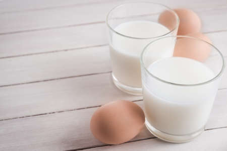 Glass of milk and eggs on tableの写真素材