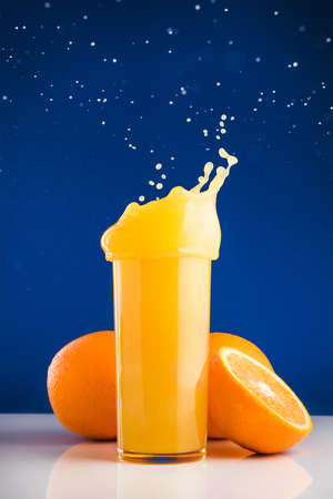 Fresh orange juice with splash on blue backgroundの写真素材