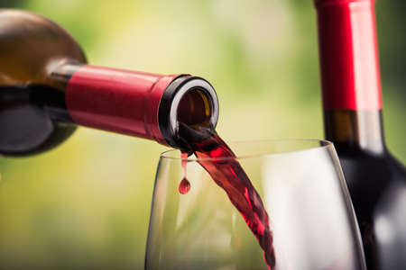 Poured red wine into glass on natural backgroundの写真素材