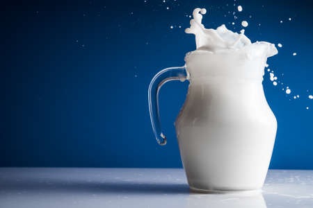 Carafe with milk splash on white tableの写真素材