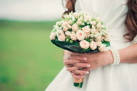 Bride holding a wedding bouquet of roses flowersの写真素材