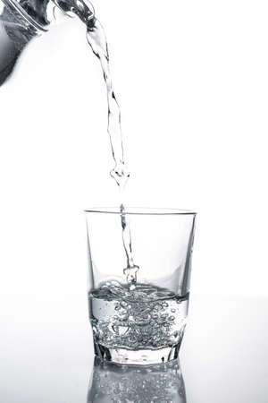 Poured water into glass isolated on white backgroundの写真素材