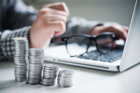Stack of silver coins an office desk on the background of working manの写真素材