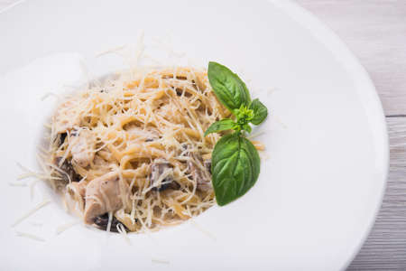 pasta with chicken and mushrooms on white plateの写真素材