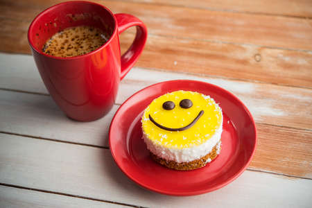 Coffee red cup and smile cake on wood table. Morning tasty breakfast.の写真素材