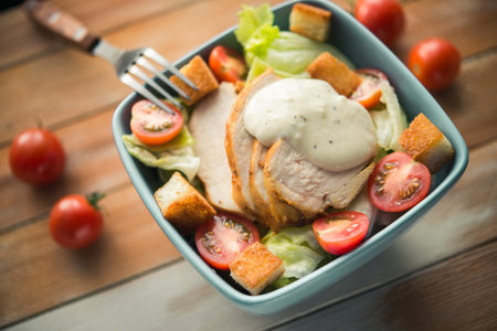 Caesar salad with chicken and tomato on wooden tableの写真素材